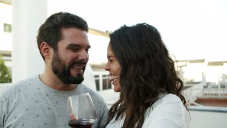 Happy-young-couple-toasting-to-camera-and-drinking-red-wine